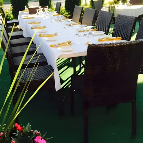 Long outdoor dining table at Ancona Bistro set with white tablecloths, plates, and golden napkins.